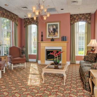 A traditionally styled living room with a warm color palette, featuring a chandelier, fireplace, and elegant furnishings.