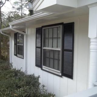 A residential house with white siding and black shuttered windows.