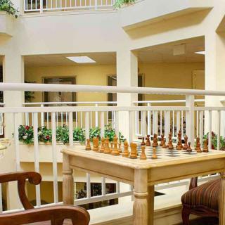 A chess set arranged on a wooden table in an indoor atrium area.