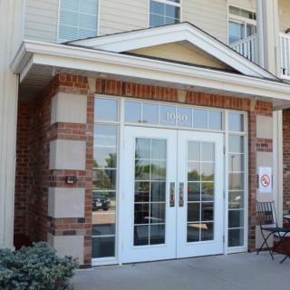 Front entrance of a building with glass double doors and brick accents.