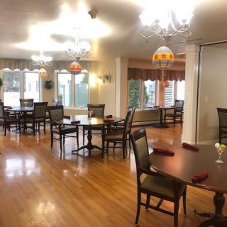 A well-lit dining room with several tables and chairs on a wooden floor.