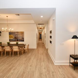 A spacious and modern interior view showcasing a dining area with elegant lighting, leading into a well-lit hallway.