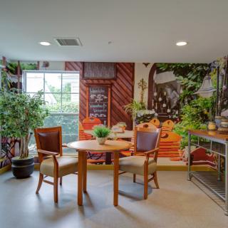 A cozy dining area with wooden furniture and lush indoor plants, complemented by a vibrant mural on the wall.