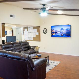 A cozy living room with a leather sofa, television, and ceiling fan.