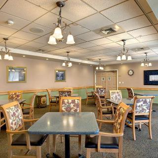 A cozy restaurant dining area with neatly arranged tables and chairs, illuminated by stylish ceiling lights.