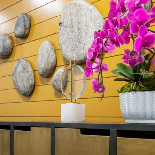 A modern interior decor featuring vibrant pink orchids and abstract wall art.