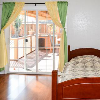 A bedroom with a single bed and sliding glass doors leading to an outdoor space.