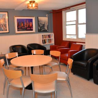 A cozy lounge area featuring a circular table surrounded by chairs and leather seating, complemented by framed artwork on the walls.