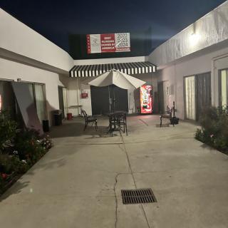 A nighttime view of a courtyard with a tent, tables, and chairs between two buildings.
