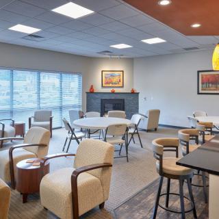 A cozy lounge area with comfortable seating, tables, and artwork on the walls.