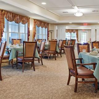 An elegantly arranged dining room with neatly set tables and upholstered chairs.