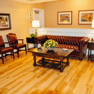 A cozy living room with a classic leather sofa, two chairs, and a wooden coffee table on a polished hardwood floor.