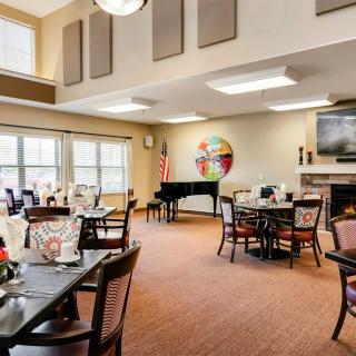 A cozy community dining area featuring a piano and a fireplace.
