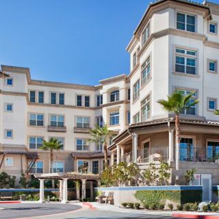 A modern residential building with palm trees in front.