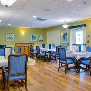 A well-lit dining room with blue upholstered chairs and wooden tables.