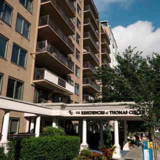 A residential apartment building with balconies and a sign reading 'The Residences at Thomas Circle'.