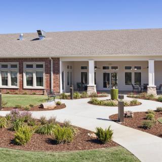 A modern building with a landscaped front yard and a winding pathway.