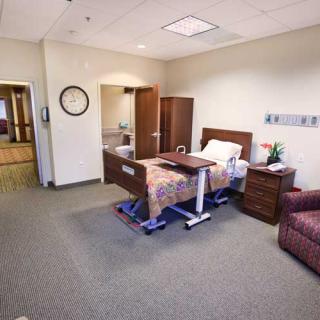 A clean and organized hospital room with a bed, side table, and armchair.