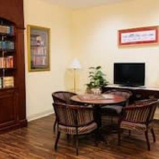 A cozy living room with a wooden bookshelf, table and chairs, TV, and a potted plant.