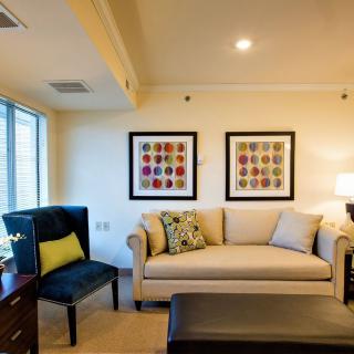 A cozy living room with a beige sofa, black armchair, and framed artwork on the wall.