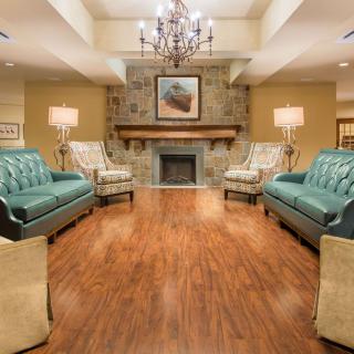A cozy living room featuring elegant sofas, a central fireplace, and a stylish chandelier.