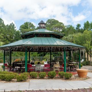 A charming gazebo set in a lush outdoor park, surrounded by greenery.