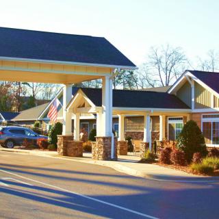 A view of a motel with a driveway and parked cars during the day.