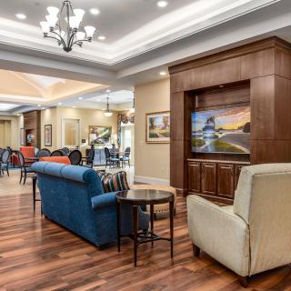 A cozy living room with elegant decor, featuring a large TV, comfortable sofas, and a chandelier.