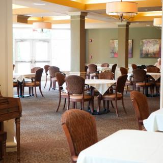 An empty restaurant dining area with neatly arranged tables and chairs, illuminated by warm lighting.