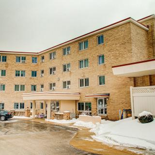 A multi-story brick apartment building with a snow-covered parking lot.
