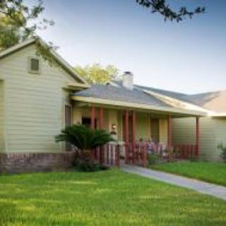 A cozy suburban house with a green lawn and front porch.
