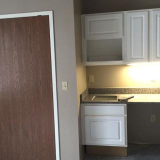 A compact kitchen space with white cabinets and a dark countertop.