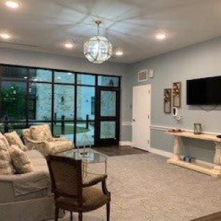 A modern living room with comfortable seating and a large TV, illuminated by a stylish chandelier.