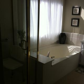 A well-lit bathroom with a large bathtub and a glass shower enclosure.