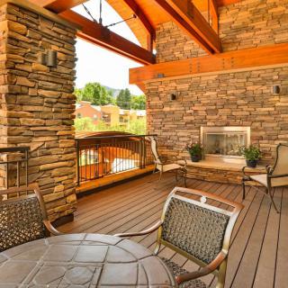 A cozy outdoor patio with a stone fireplace and comfortable seating.
