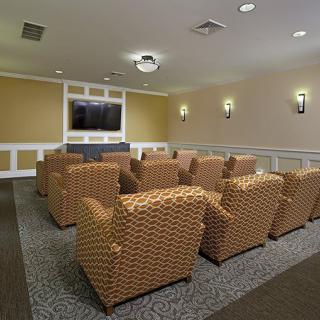 A small home theater room with multiple armchairs facing a large television screen.