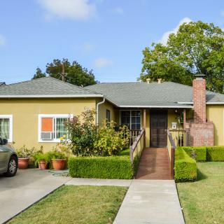 A charming single-story house with a driveway and neatly trimmed hedges.