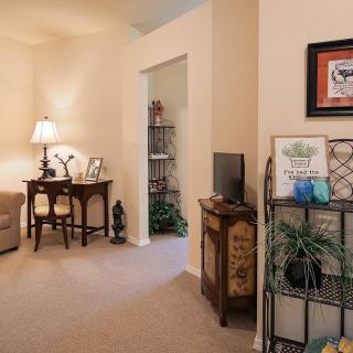 A cozy living room with a small desk, decorative items, and warm lighting.