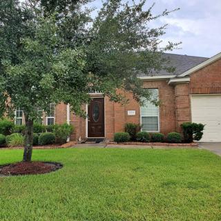 A brick house with a well-maintained lawn and front yard tree.