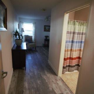 A cozy apartment hallway with a view of a decorated bathroom and seating area.