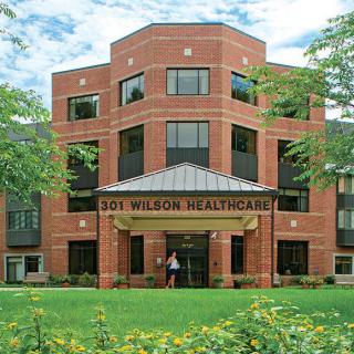 A brick healthcare facility with a well-maintained green lawn.