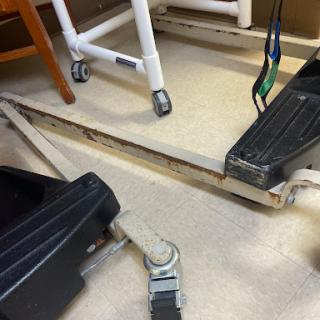 An image showing part of a wheelchair and the surrounding area in a healthcare setting.