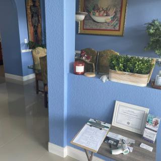 A cozy interior space featuring a blue wall, decorative plants, and framed certificates on a table.