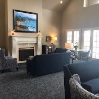 A cozy living room with sofas, a fireplace, and large windows letting in natural light.