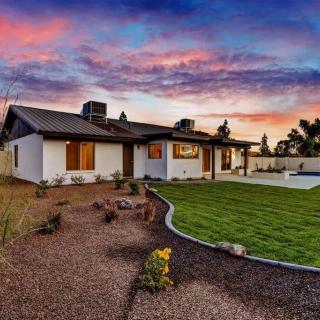 A modern house with a well-maintained yard and garden at sunset.