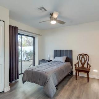 A simple bedroom with a single bed, gray bedding, and a wooden chair by the window.