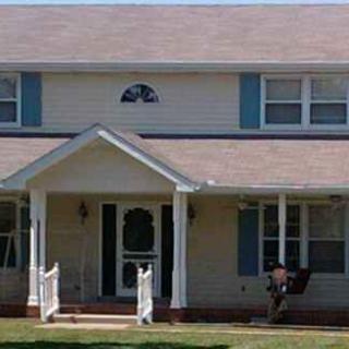 A two-story suburban house with a front porch and blue shutters.