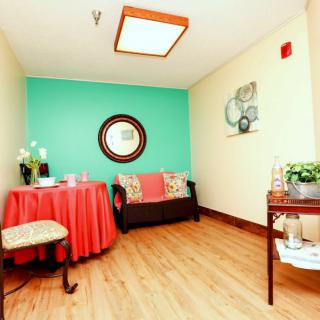 A cozy waiting room with a teal accent wall, sofa, and decor elements like a mirror and plants.