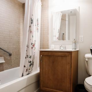 A cozy bathroom with a wooden vanity, a floral shower curtain, and bright lighting.