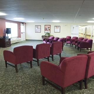 An empty lounge area with rows of red chairs facing a television.